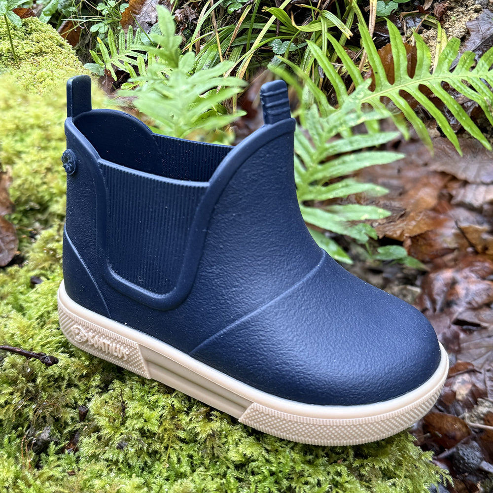 Image of a pair of Boatilus Baby Beatly boots in navy and white on a patch of grass