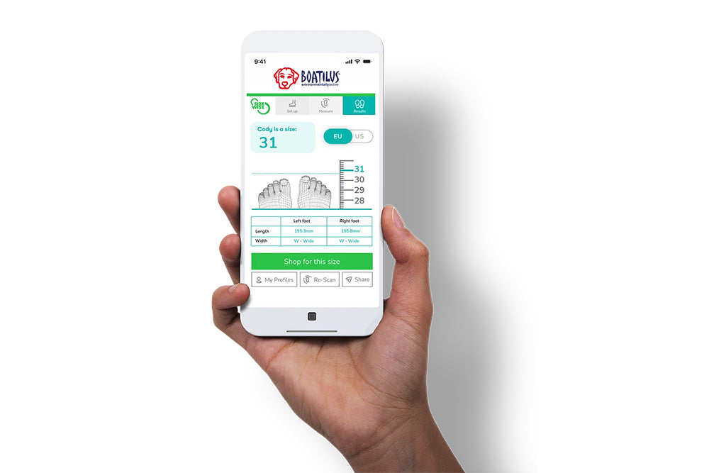 A hand holding a smartphone showing the Boatilus UK website and size guide information.